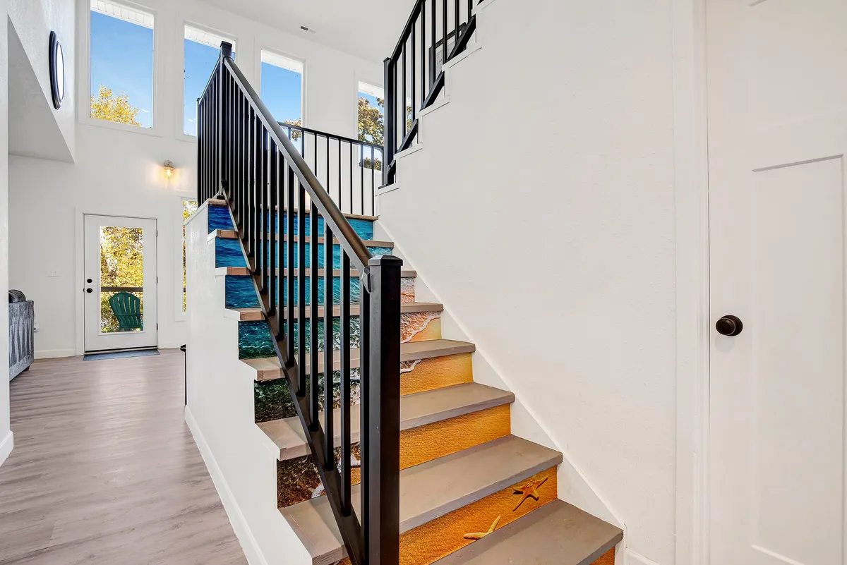 This interior shot looks toward the front door, staircase, and large windows, capturing the transitional space where guests enter and exit. The setup hints at where security panels and monitors could be discreetly installed.